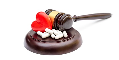 Gavel with red heart and pills on white. Medical law concept.