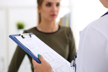 Female doctor hand holding and filling patient history list at clipboard pad during physical. Exam, er, disease prevention, ward round, visit check, 911, prescribe remedy, healthy lifestyle concept