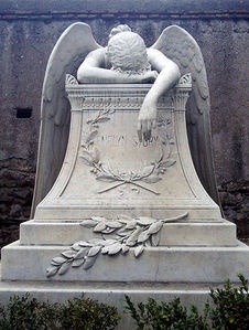 A Tombstone with an angel mourning on top of it.