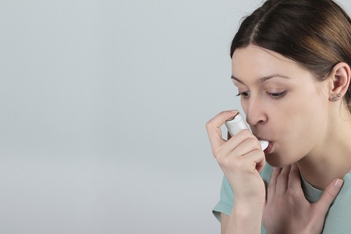 Young woman using an inhaler during an asthma attack.