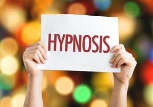 Conversational Hypnosis article Photo of a woman holding up a sign that reads HYPNOSIS