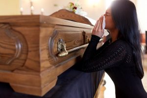 Woman in grief, crying kneeling down at a casket, grief counseling courses page
