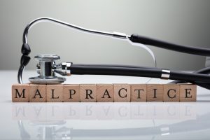 Stethoscope Over Malpractice Wooden Block