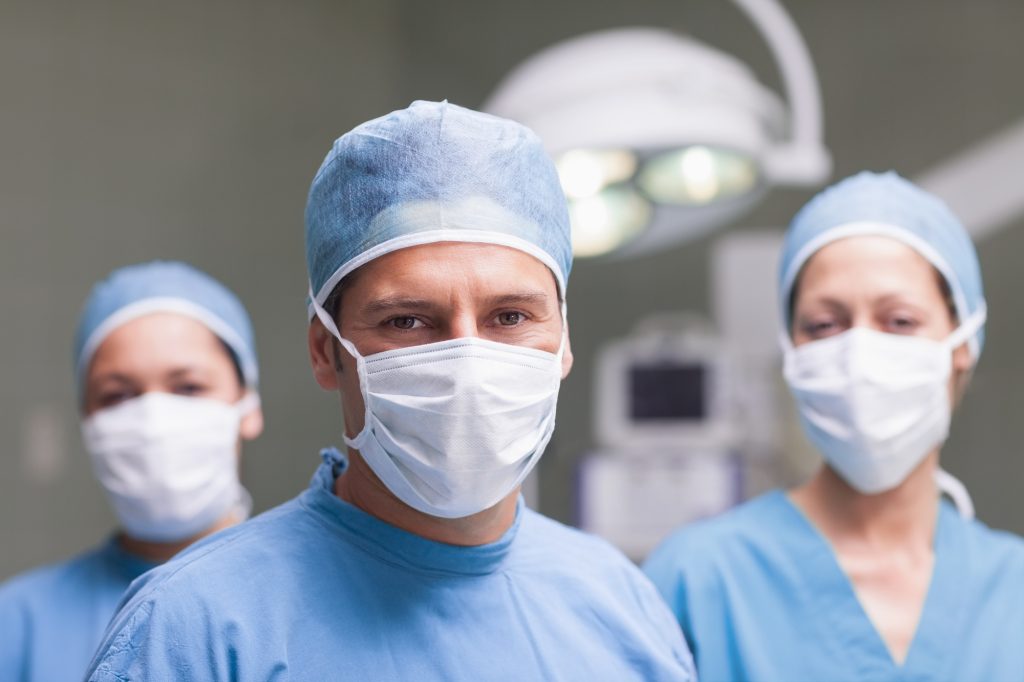 Medical team looking at camera in operating theater