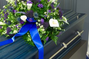 A blue coffin with flowers on top of it