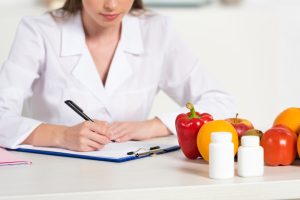 A nurse reviewing a file with fruit and vegetables near her.