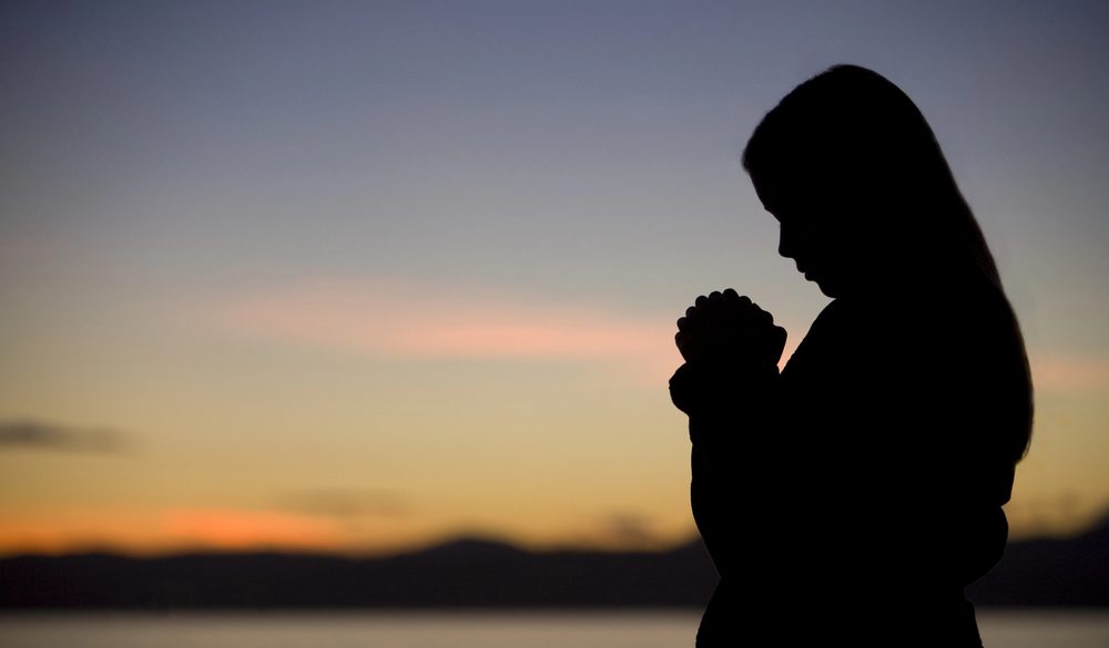 Woman praying at sunrise