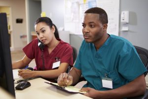 Two nurses studying to become a health care Manager at a computer.