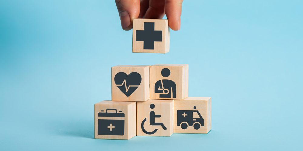 A hand placing blocks with medical symbols on top of one another