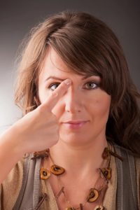 head shoulders photo of a woman demonstrating how to do EFT showing a tapping point on the right eye brow point