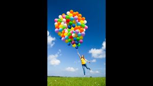 Girl being lifted off the ground by a large bunch of balloons