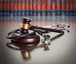 Gavel and stethoscope in front of legal textbooks