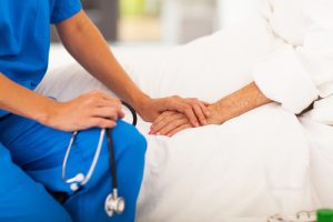 A nurse holding the hand of a dying patient