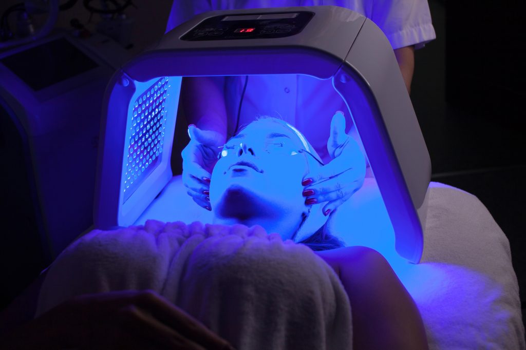 Young woman having LED light facial treatment