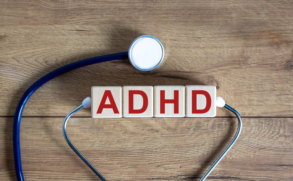ADHD symbol. Concept word 'ADHD, Attention Deficit Hyperactivity Disorder' on cubes on a beautiful wooden background. Stethoscope. Copy space, medical and ADHD concept.
