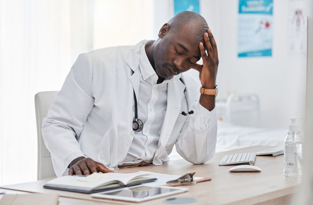 Stress, anxiety and sad doctor, medical professional and healthcare worker with negative test results on technology. Thinking with burnout headache or bad news in clinic, hospital or health center.