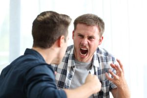 Two guys that need anger management consulting. They are screaming at each other with balled up fists.