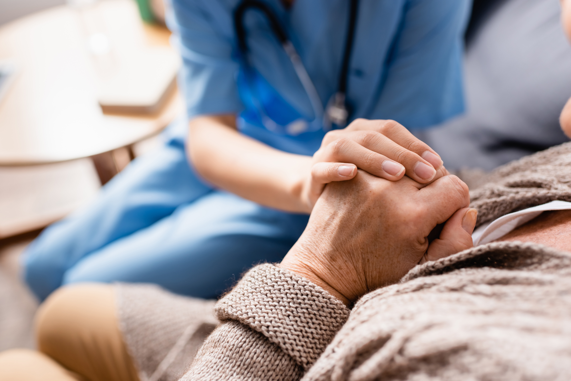 Nursing home nurse holding hands with a patient