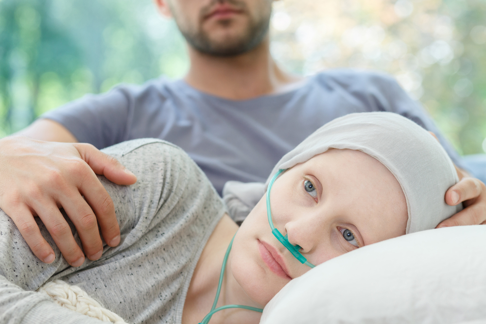 Woman with oxygen nasal cannula and headscarf lying on couch