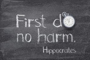 Health Care Ethics Motto: First do no harm - ancient Greek physician Hippocrates quote written on chalkboard with stopwatch symbol instead of O