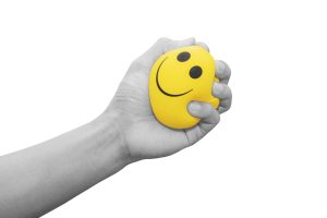 Stress Management Coaching: A hand squeezing a yellow stress ball.