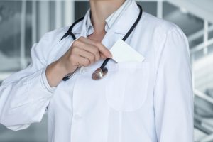 A Healthcare professional pulling a business card out of their pocket. 