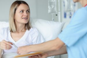 A patient in a hospital bed filling out a form with a case manager.