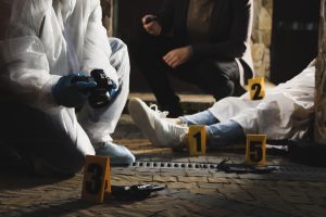 A forensic nurse and criminologist working at crime scene with dead body outdoors, closeup