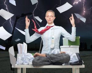 Effective Ways to Reduce Stress? A picture of a business lady tossing papers in the air as she meditates on her desk. 