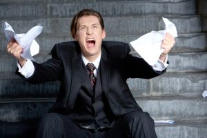 Classic photo of a man screaming as he rips a piece of paper apart in frustration. 