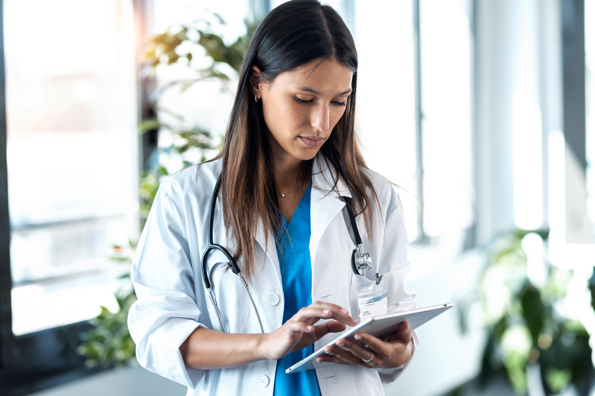 Shot of confident young female doctor reviewing the patient's medical history on her digital tablet while standing in the consultation.