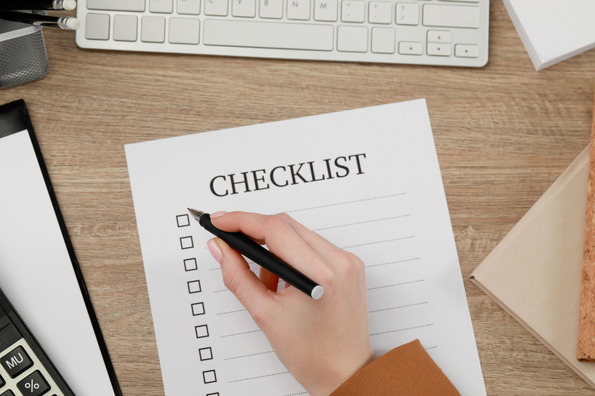 Woman filling Checklist at wooden table, top view