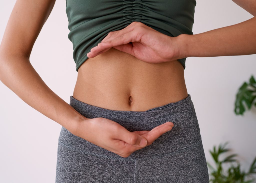 Close up of a young multi-ethnic woman's stomach cupped by her hands. High quality photo