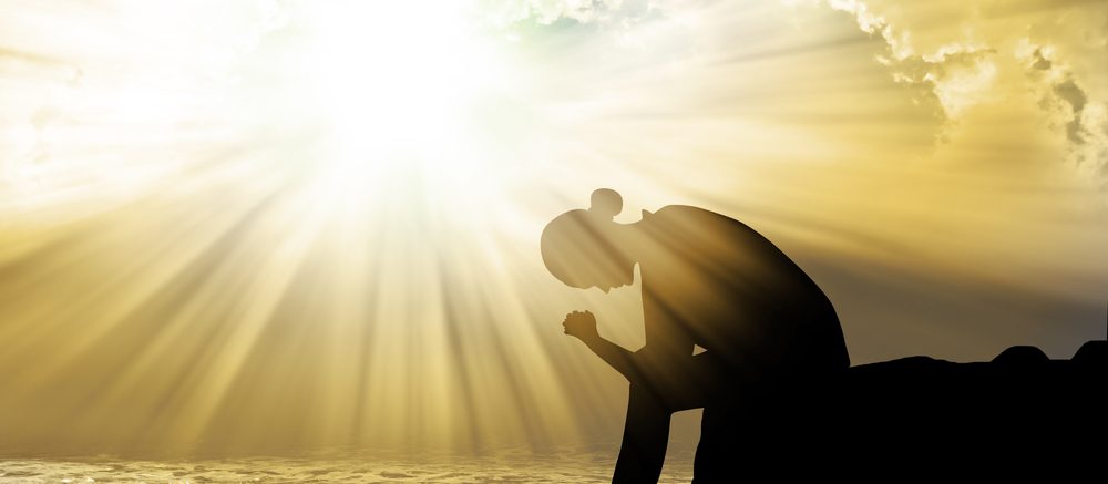 Shadow of a woman praying in the sunlight