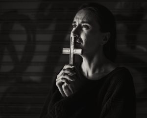 Woman praying with a cross