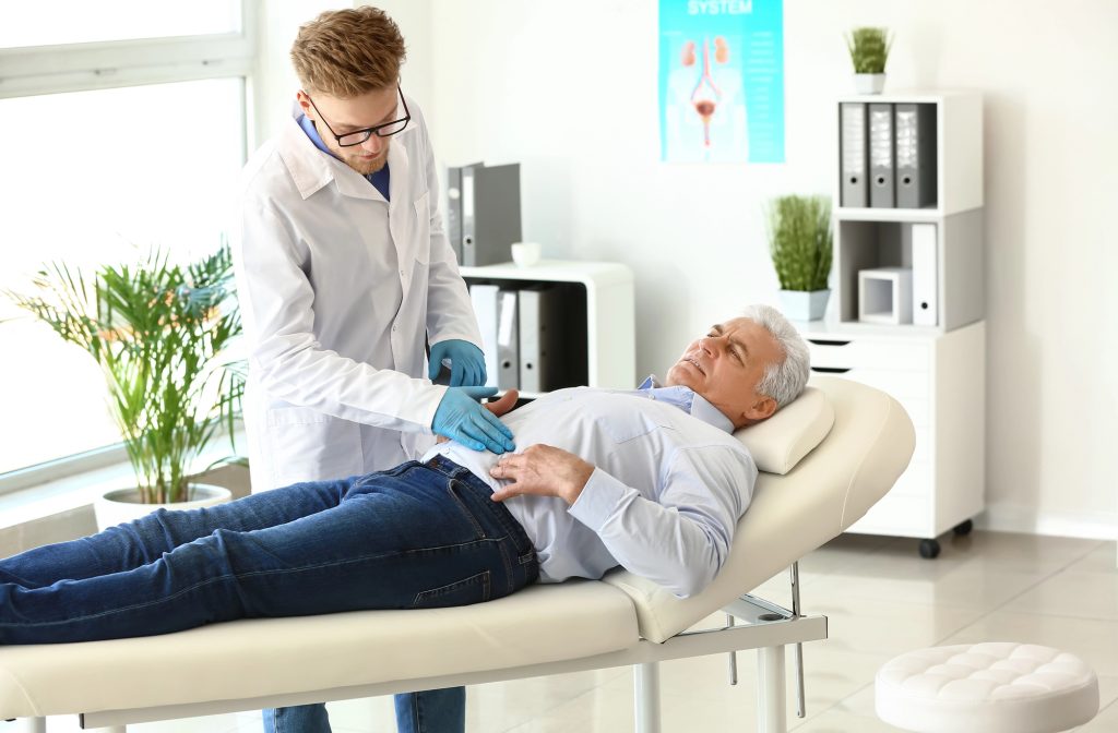 Urologist examining male patient in clinic
