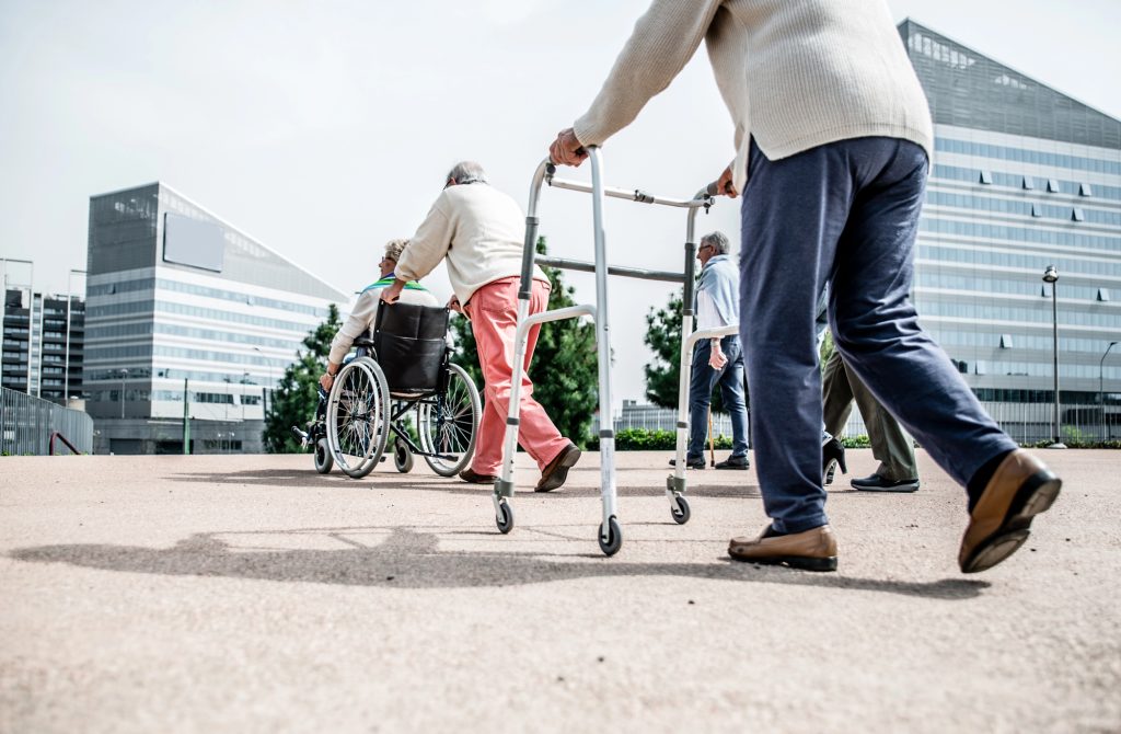 Old people going for a walk using walkers, canes and wheelchairs