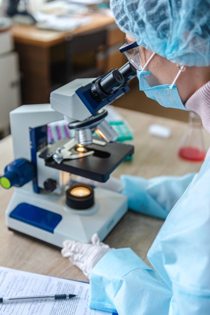 Female scientist studying coronavirus. The doctor looks through a microscope at a vaccine against coronavirus.